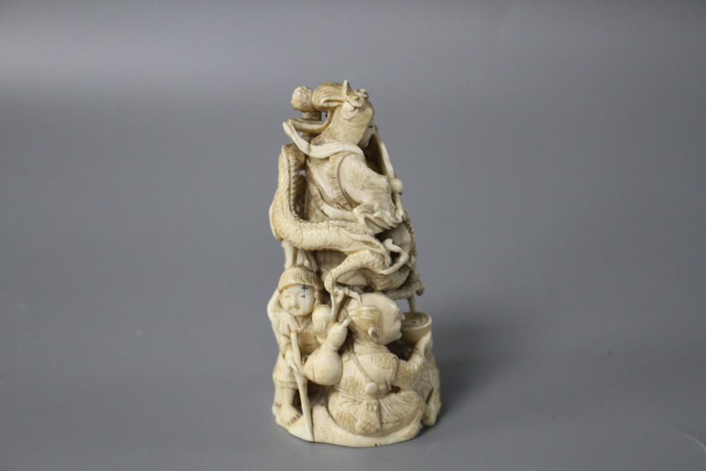 A Japanese Meiji period carved ivory group of a goddess and dragon with attendants, signed to the underside, height 8cm